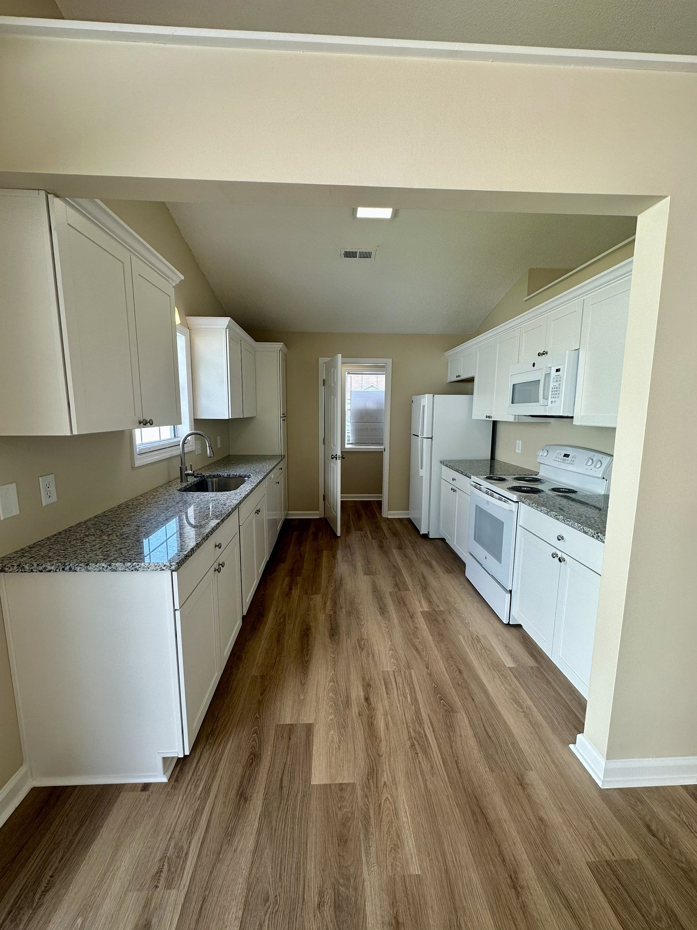 Kitchen after JICON remodel — white shaker cabinets, granite counters and new flooring